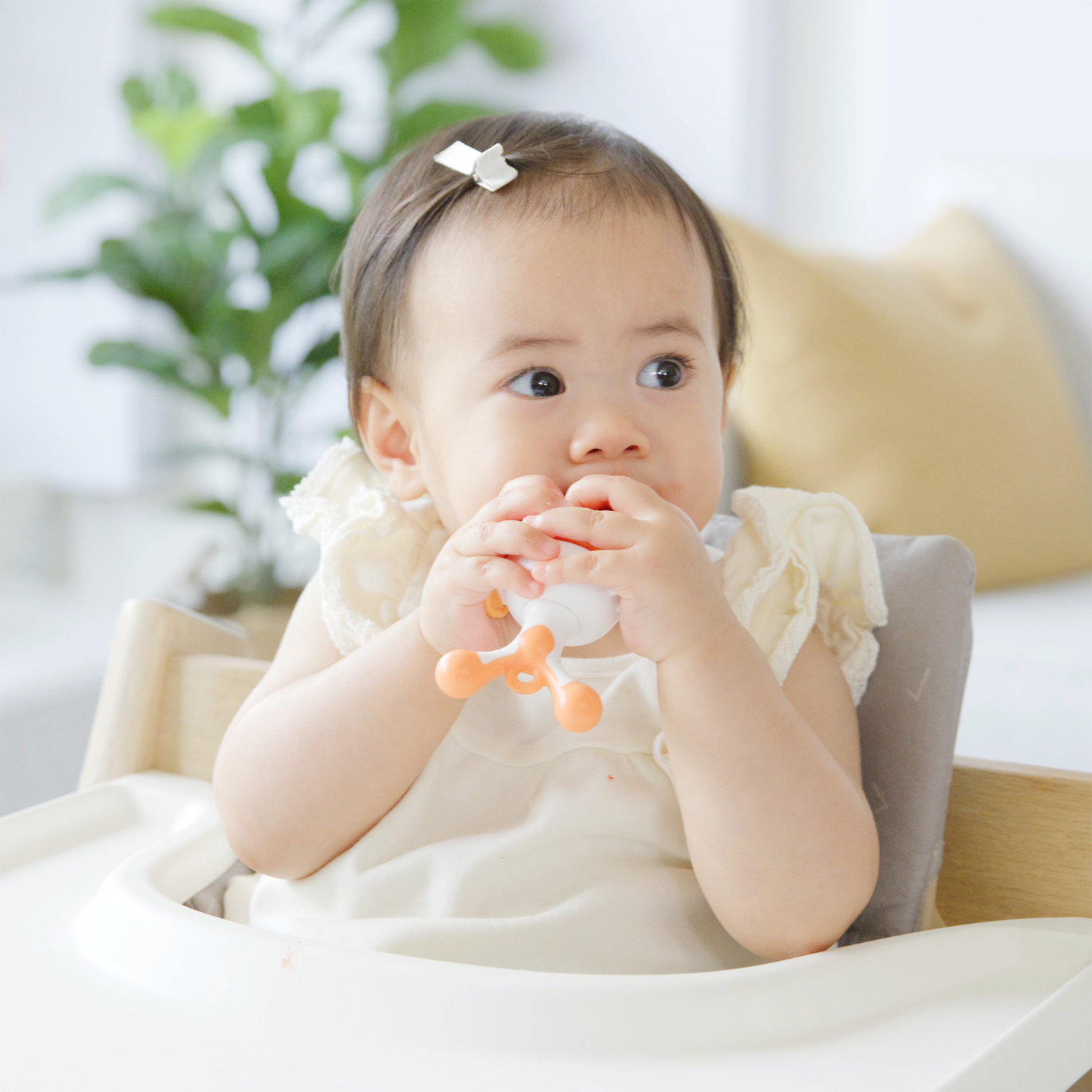 Quark Baby teething toy with orange details, infant holding and chewing during solids introduction stage