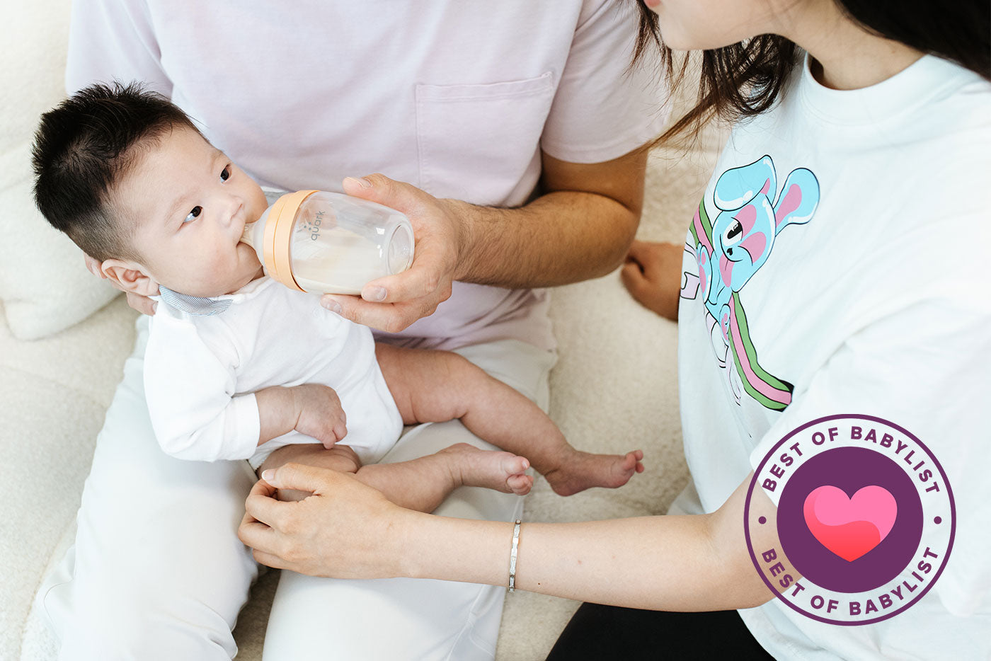 Adult feeding infant with Quark Baby BuubiBottle Hybrid Feeding System, award-winning innovative baby bottle design.