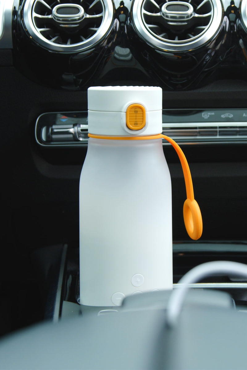 Quark BuubiBottle white portable milk warmer clipped to a car dashboard air vent, useful for daycare runs