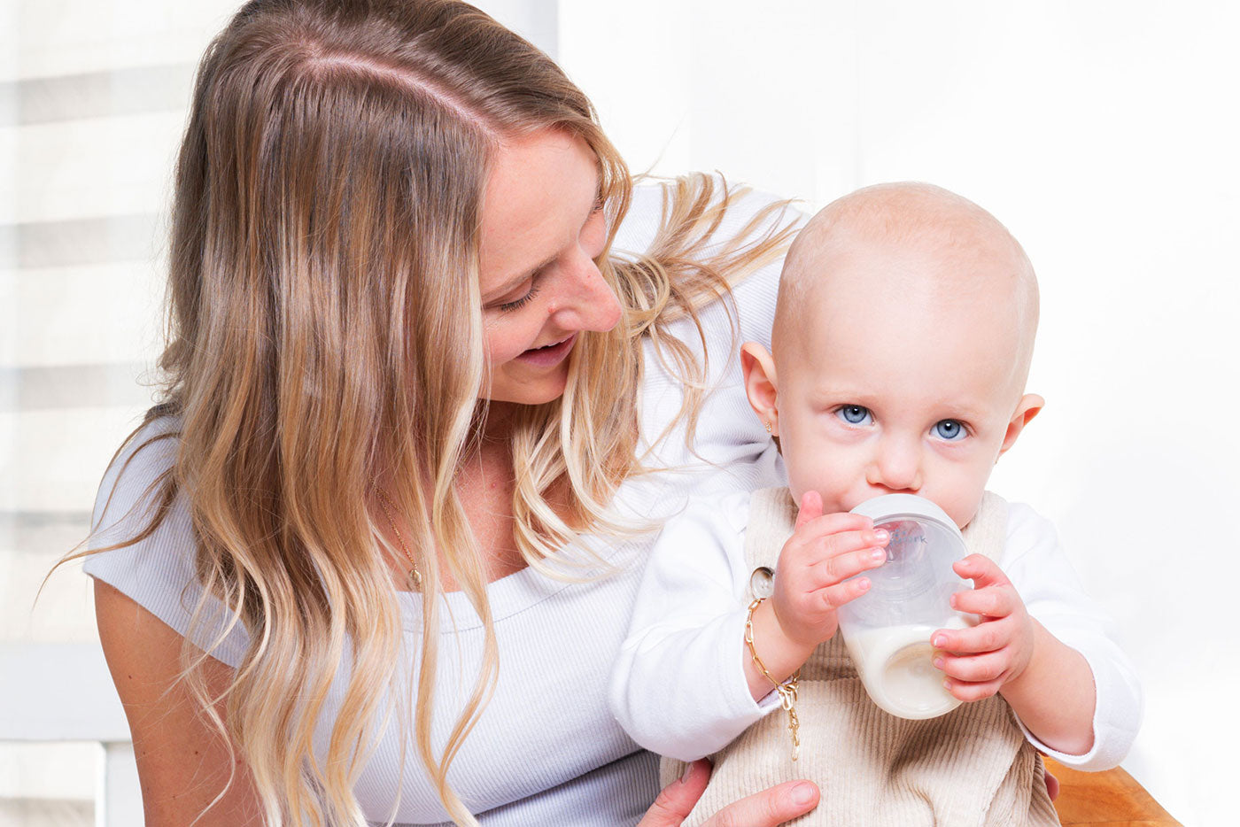 Mother feeding infant with Quark Baby bottle during breastfeeding transition, lifestyle shot
