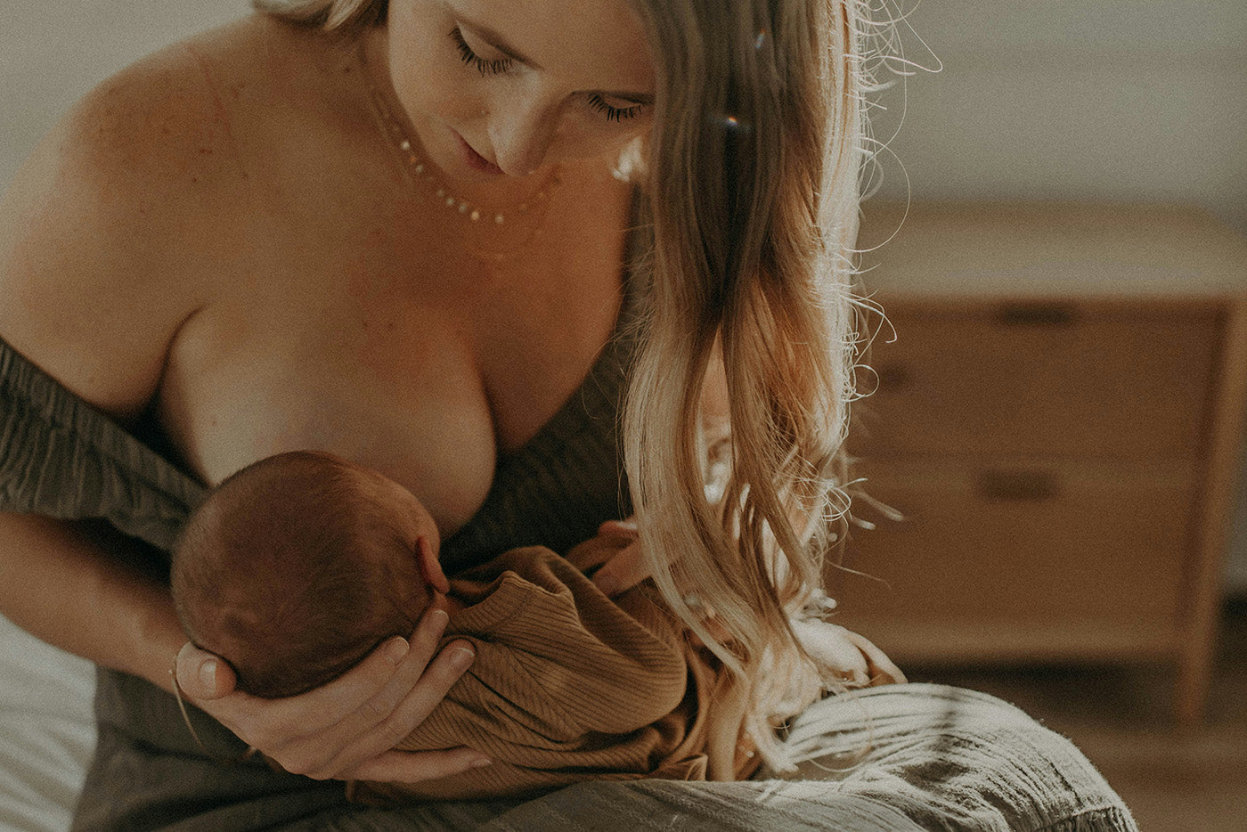 Mother breastfeeding newborn infant in warm home setting, Quark Baby lifestyle