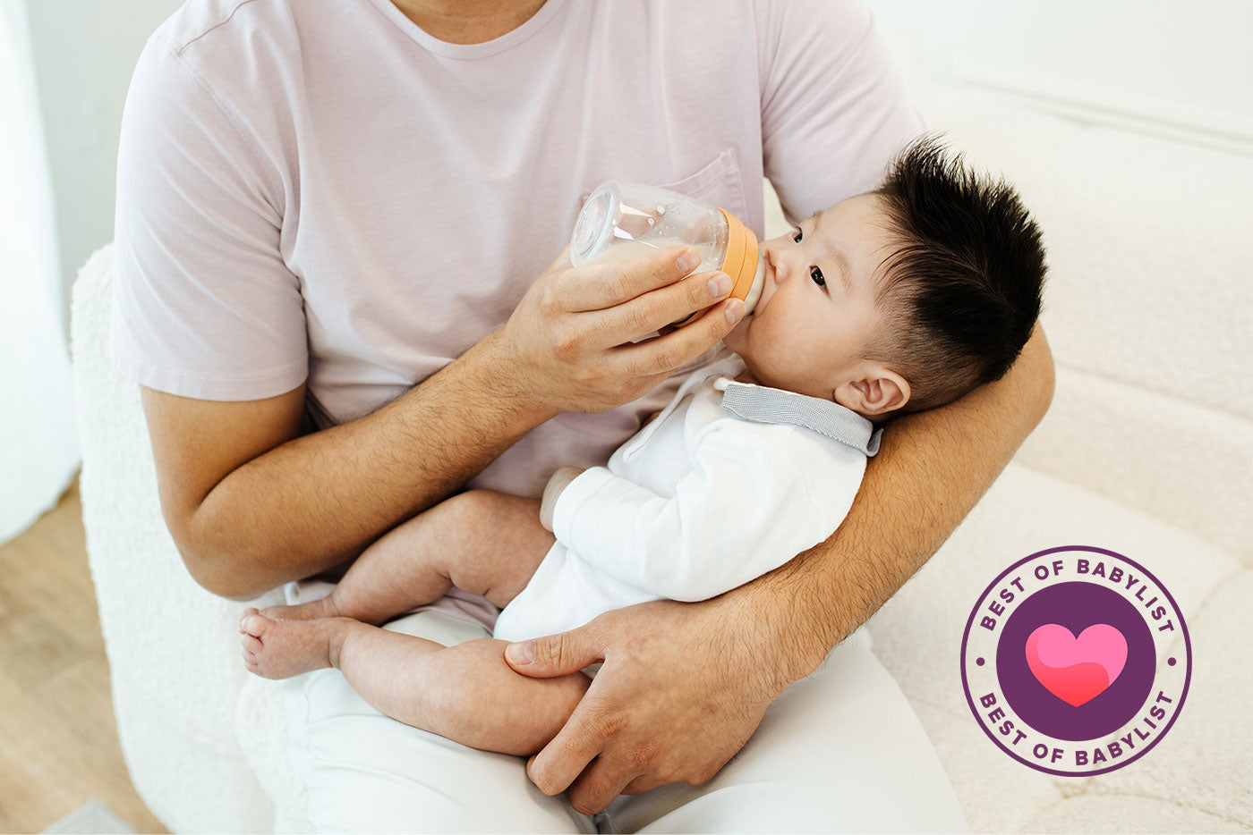 Adult feeding infant with Quark Baby BuubiBottle Hybrid Feeding System bottle in lifestyle shot.