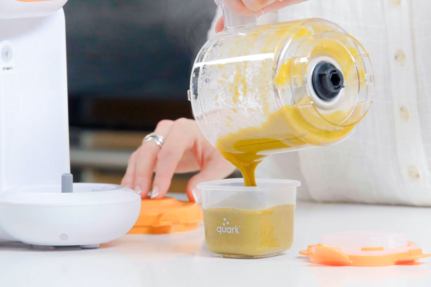 Quark Baby food maker dispensing broccoli sweet potato purée into container for baby feeding.