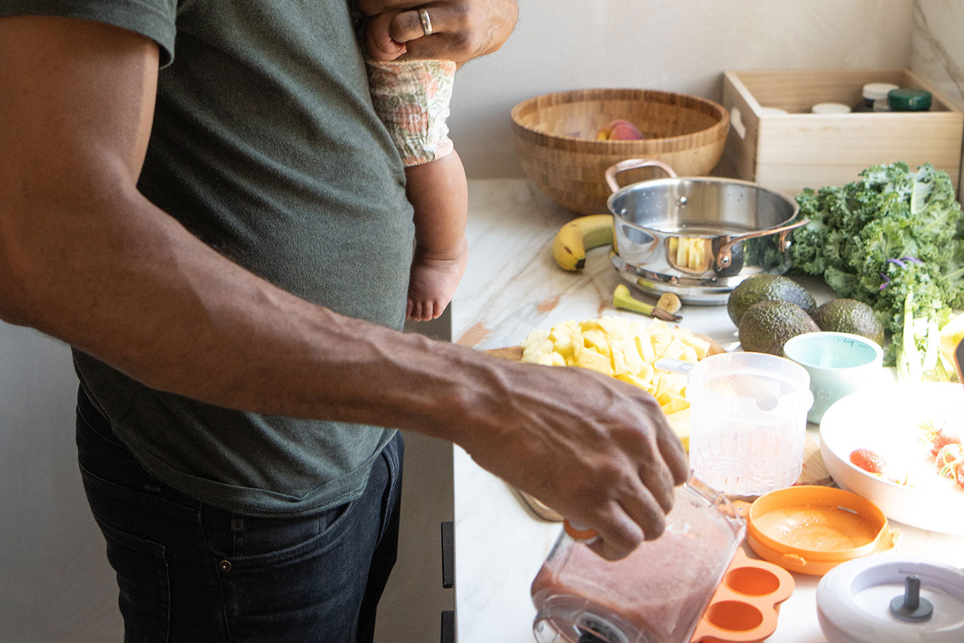 Adult preparing homemade baby food with Quark Baby storage containers and fresh ingredients in kitchen.
