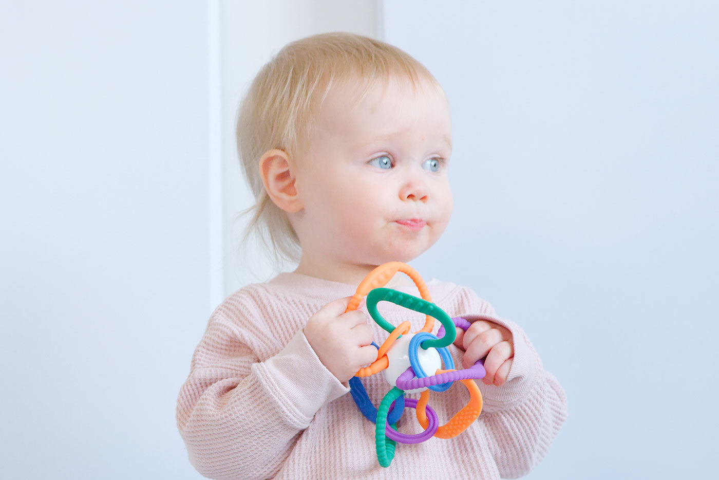 Quark Baby Thiingy colorful sensory teething ball with nine rings and soft rattle in infant's hands