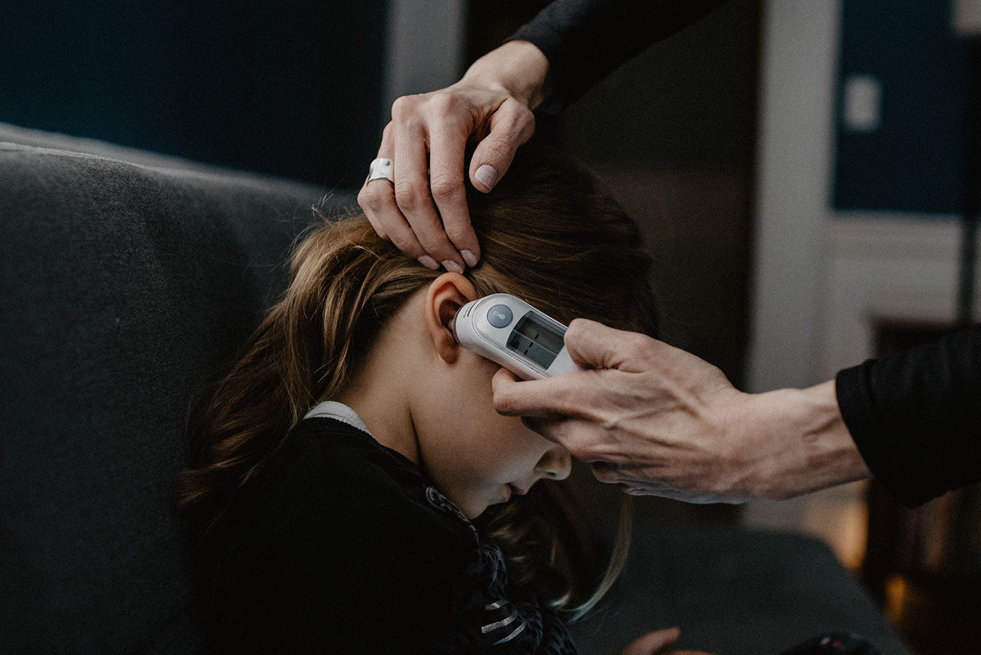 Adult checking child's forehead temperature with Quark Baby thermometer during illness care