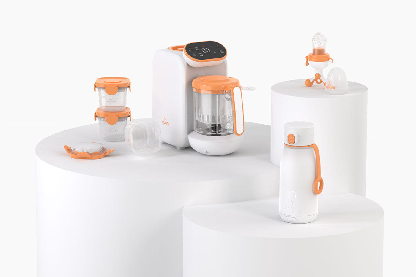 Quark Baby innovative feeding accessories collection with orange accents displayed on white pedestals.