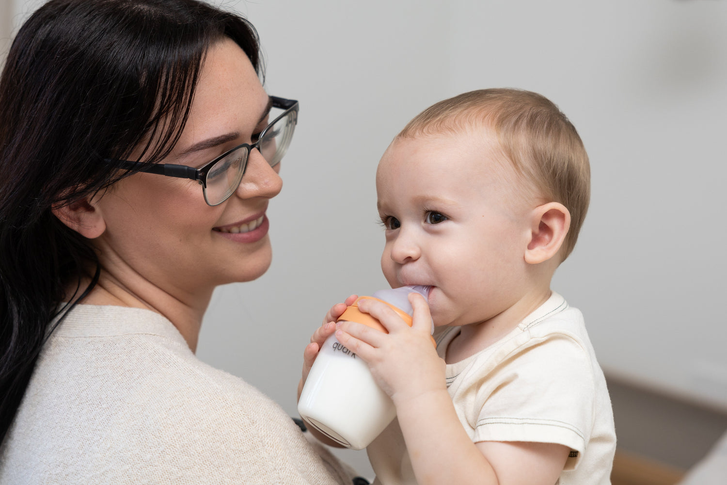Adult holding Quark Baby bottle while infant drinks, teething relief lifestyle scene