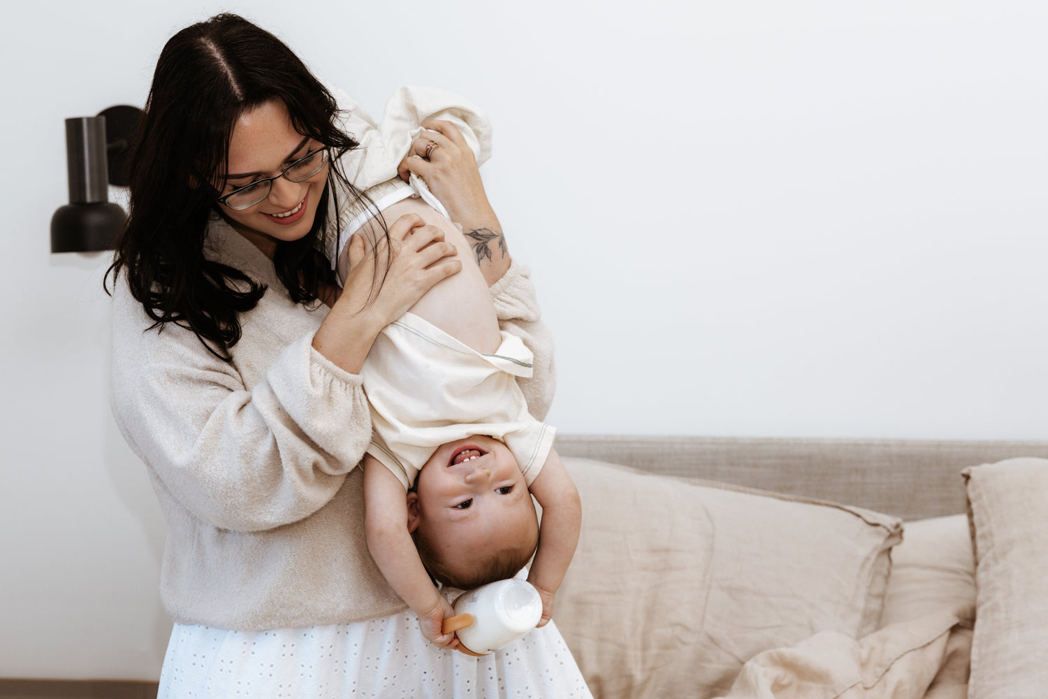Mother playing with infant, holding Quark Baby developmental toy overhead during playtime