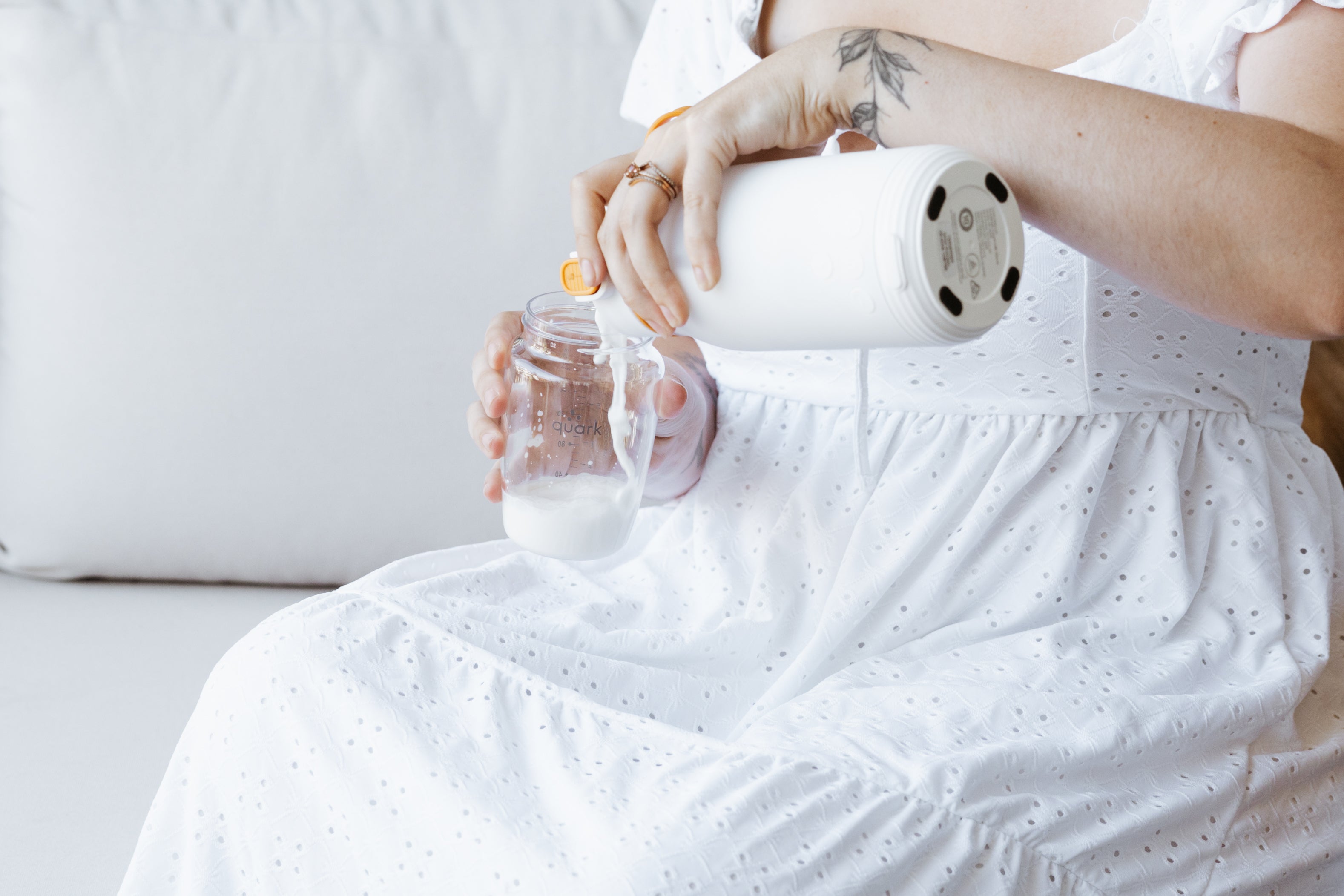 Woman holding Quark Baby bottle while pumping, hands-on nursing technique lifestyle shot.