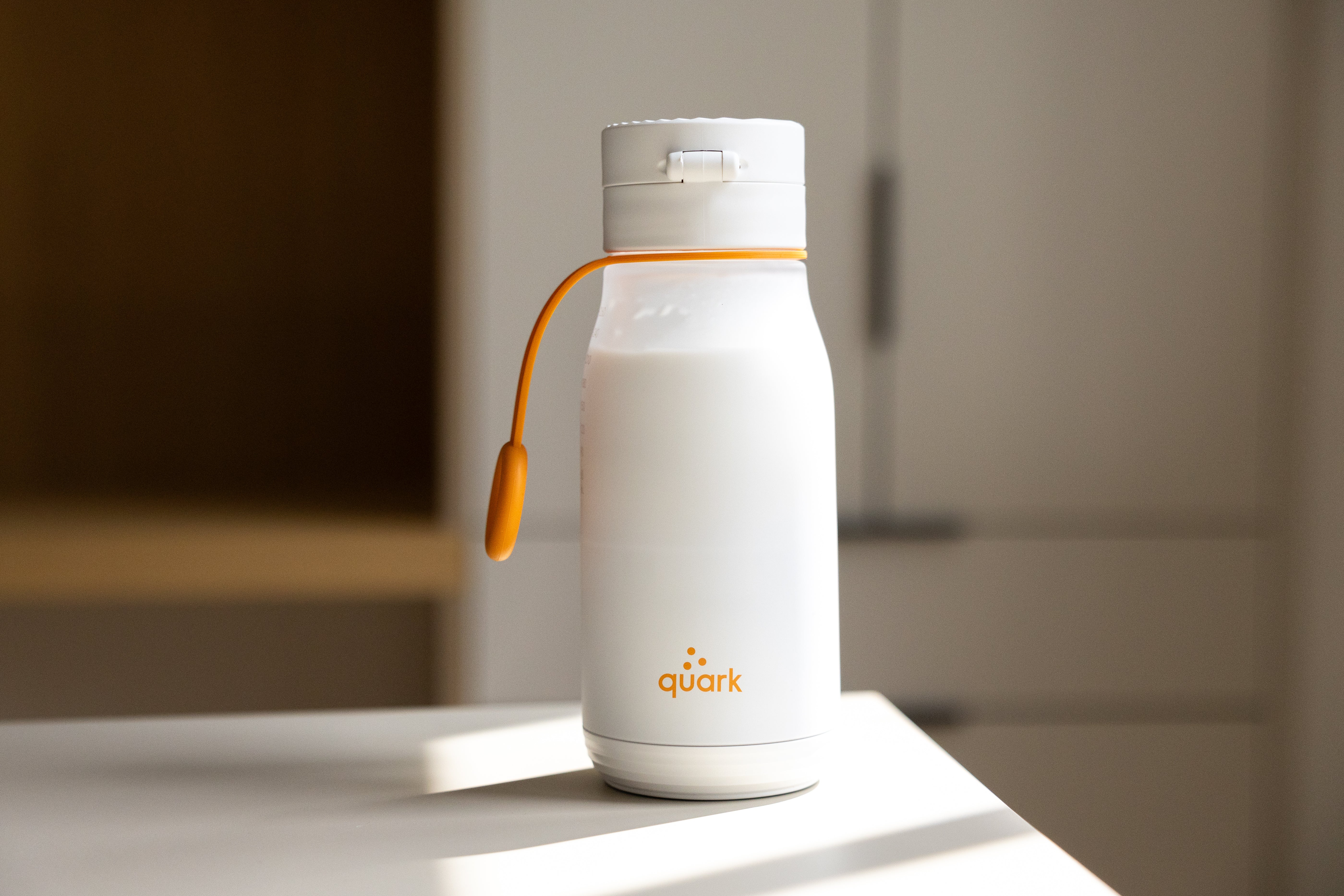 Quark Baby white bottle with orange handle on neutral surface