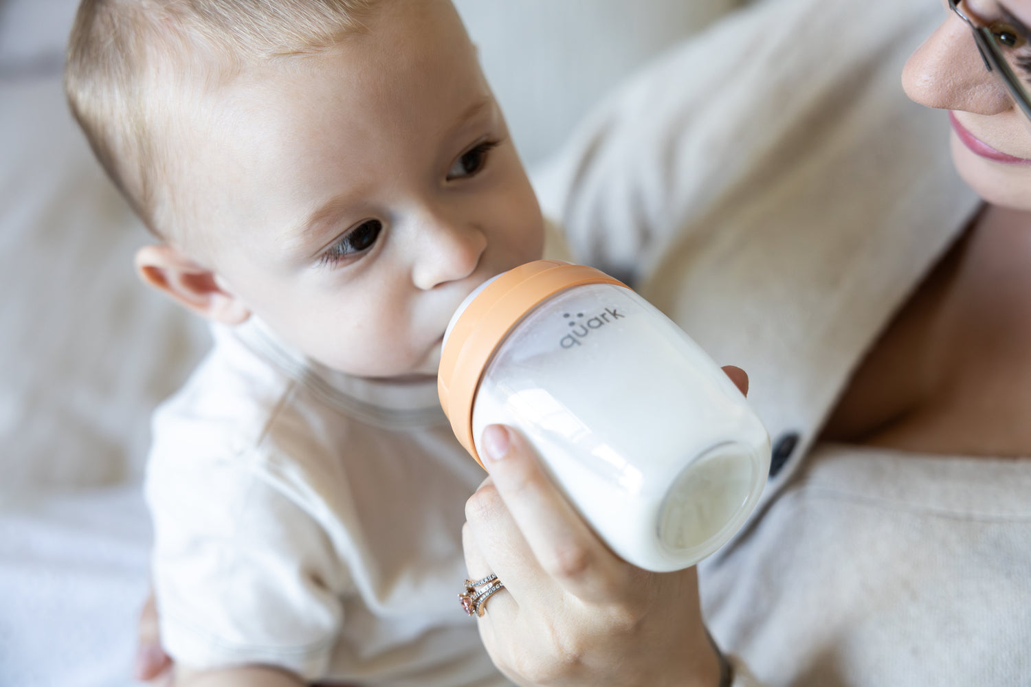 Adult feeding infant with Quark Baby bottle during combo feeding session