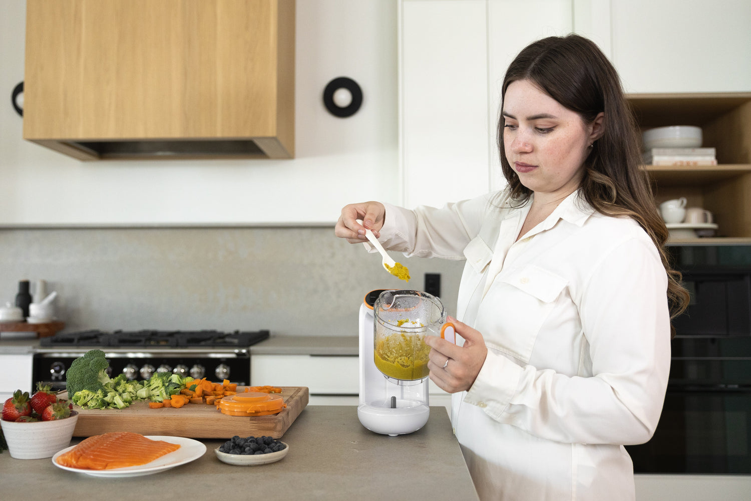 Woman blending vegetables and fruit in Quark Baby blender for homemade baby food puree.