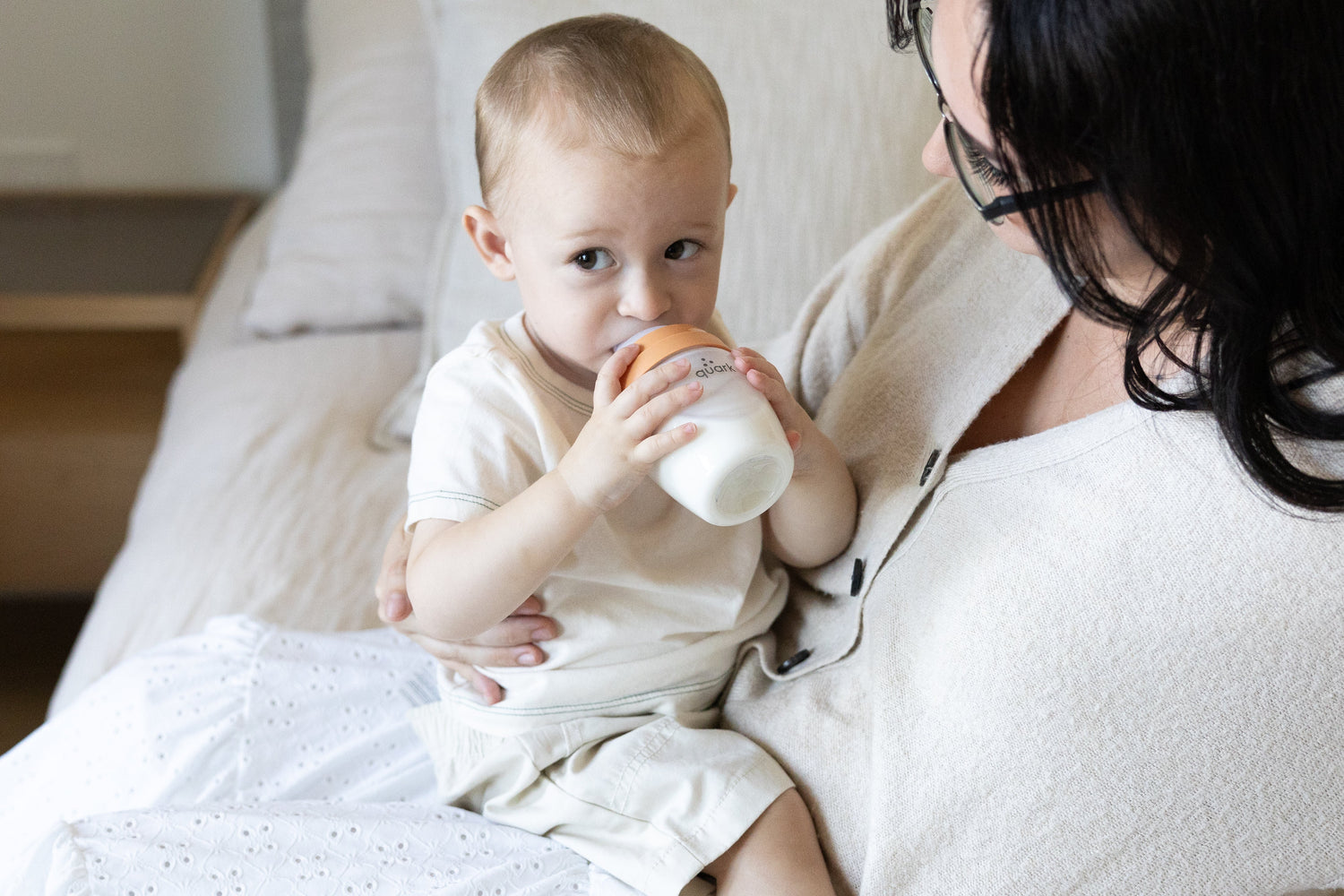 Adult feeding infant with Quark Baby bottle during breastfeeding and bottle-feeding transition.