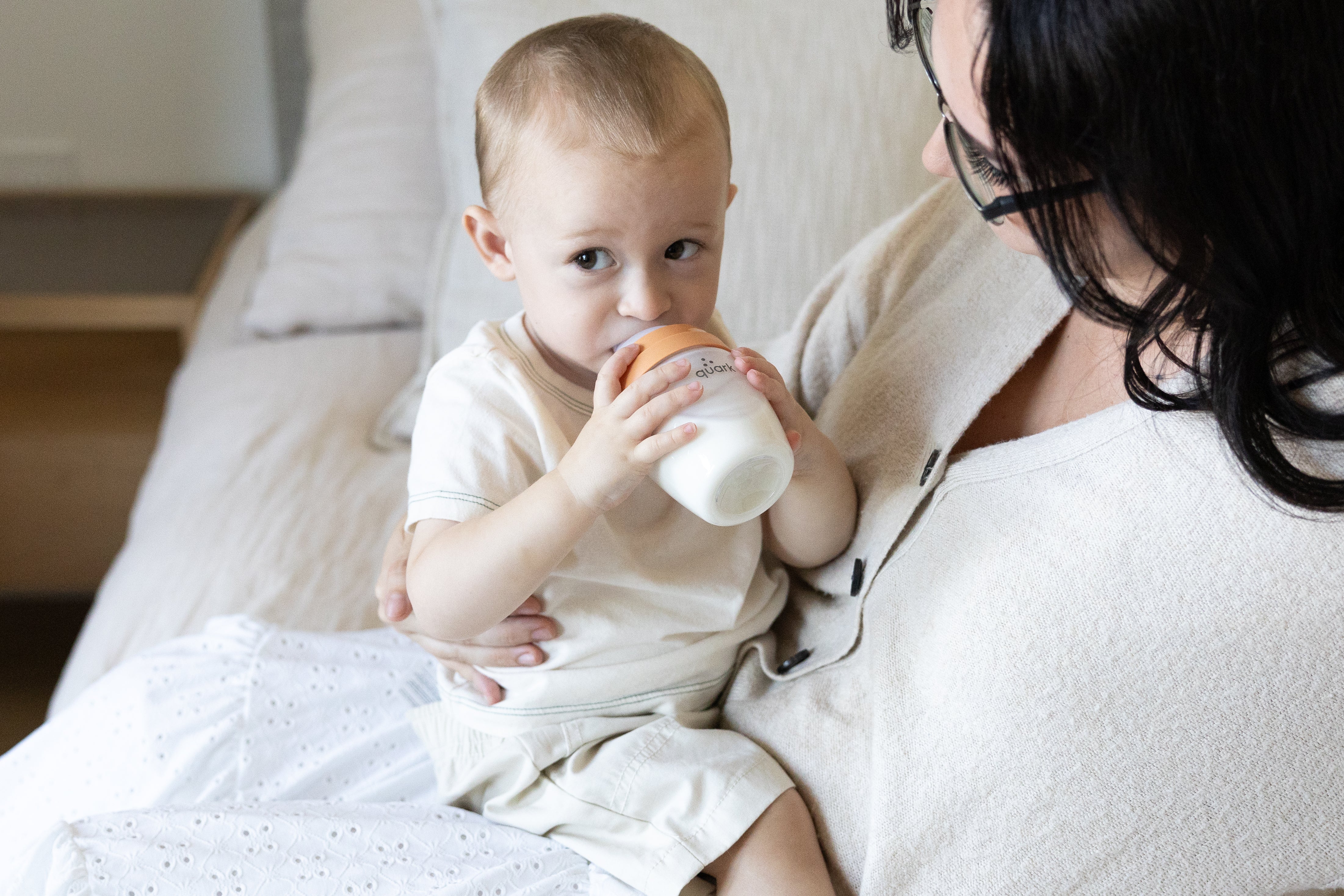Adult feeding infant with Quark Baby bottle during breastfeeding and bottle-feeding transition.