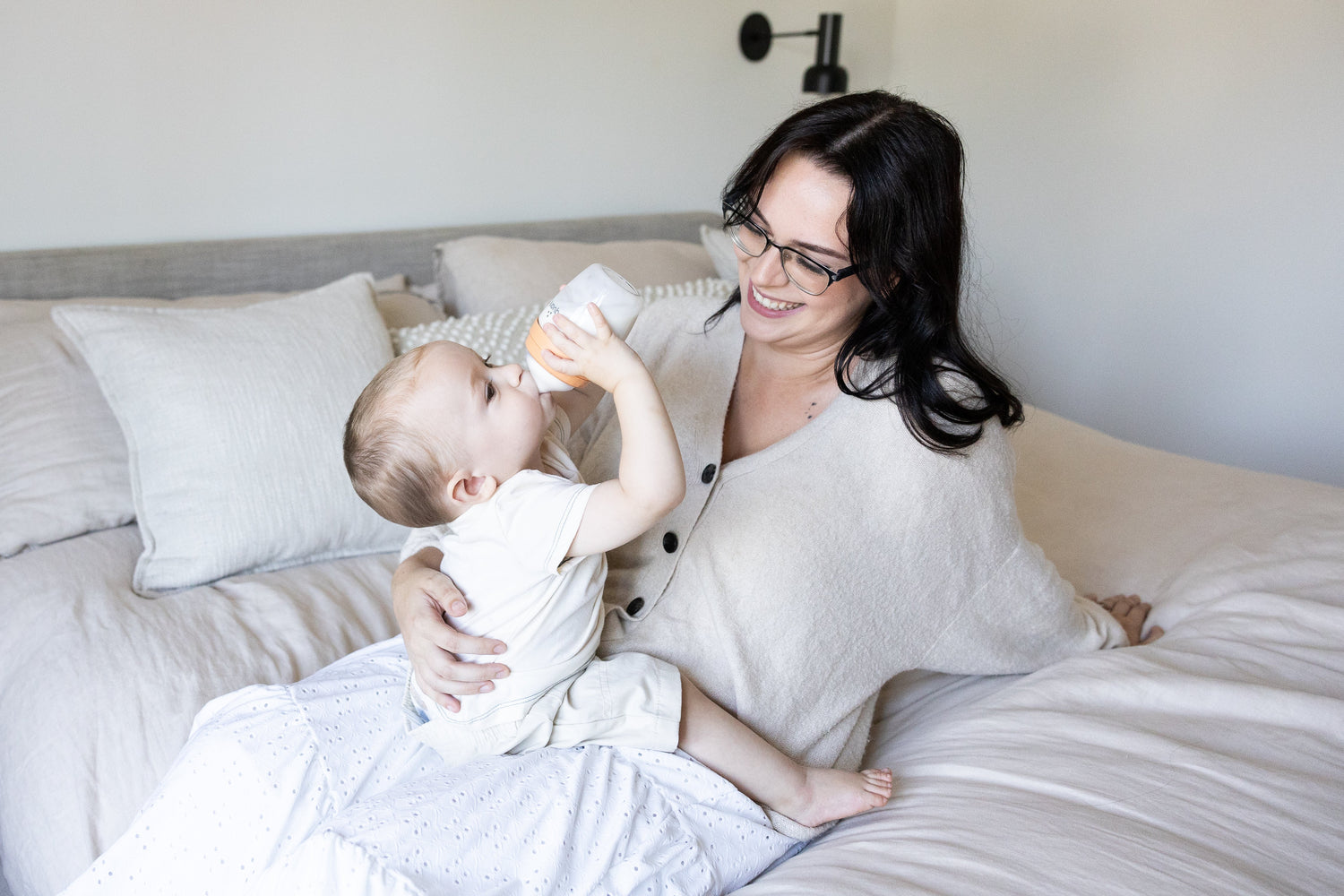 Mother feeding infant with bottle during breastfeeding education moment, Quark Baby