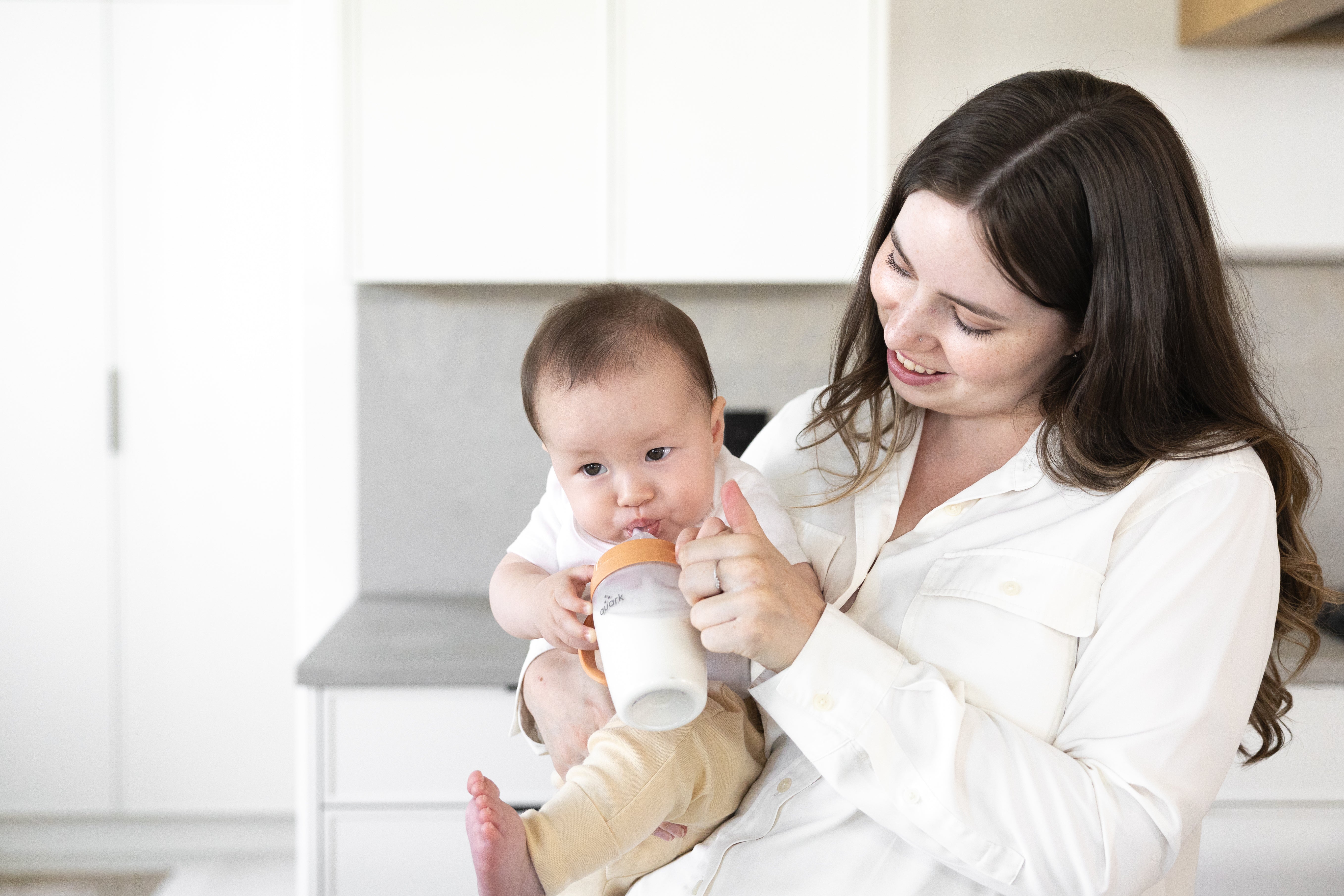Mother feeding infant with Quark Baby bottle during summer nursing session