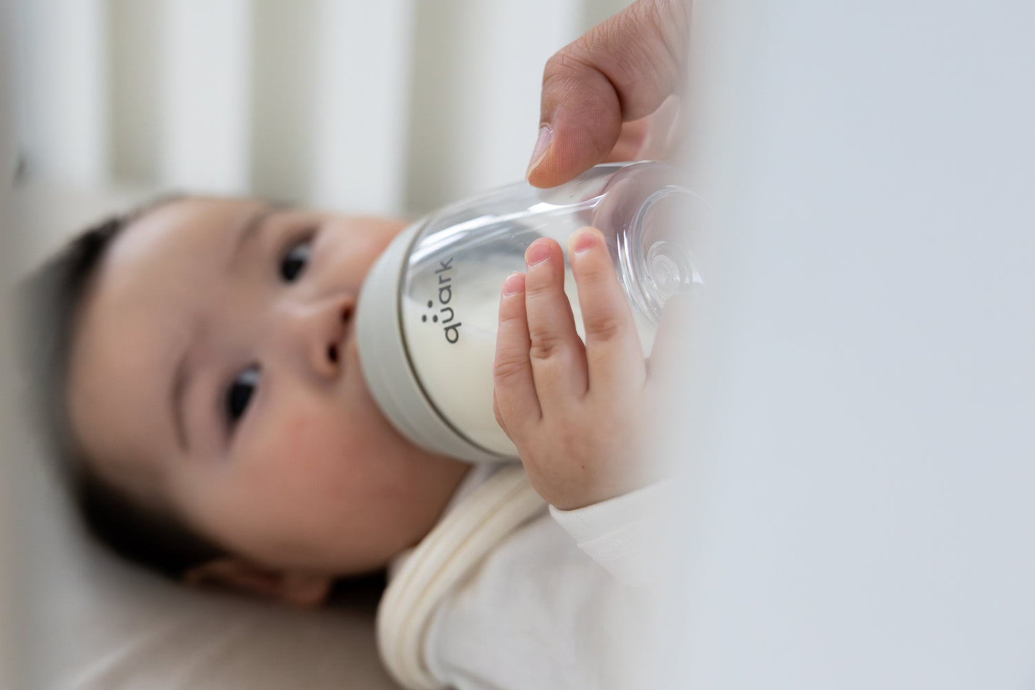 Newborn holding Quark Baby bottle with both hands during feeding