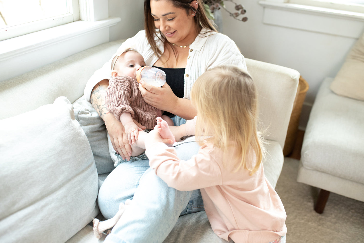 Mother and toddler with Quark Baby bottle during feeding time, bright nursery setting