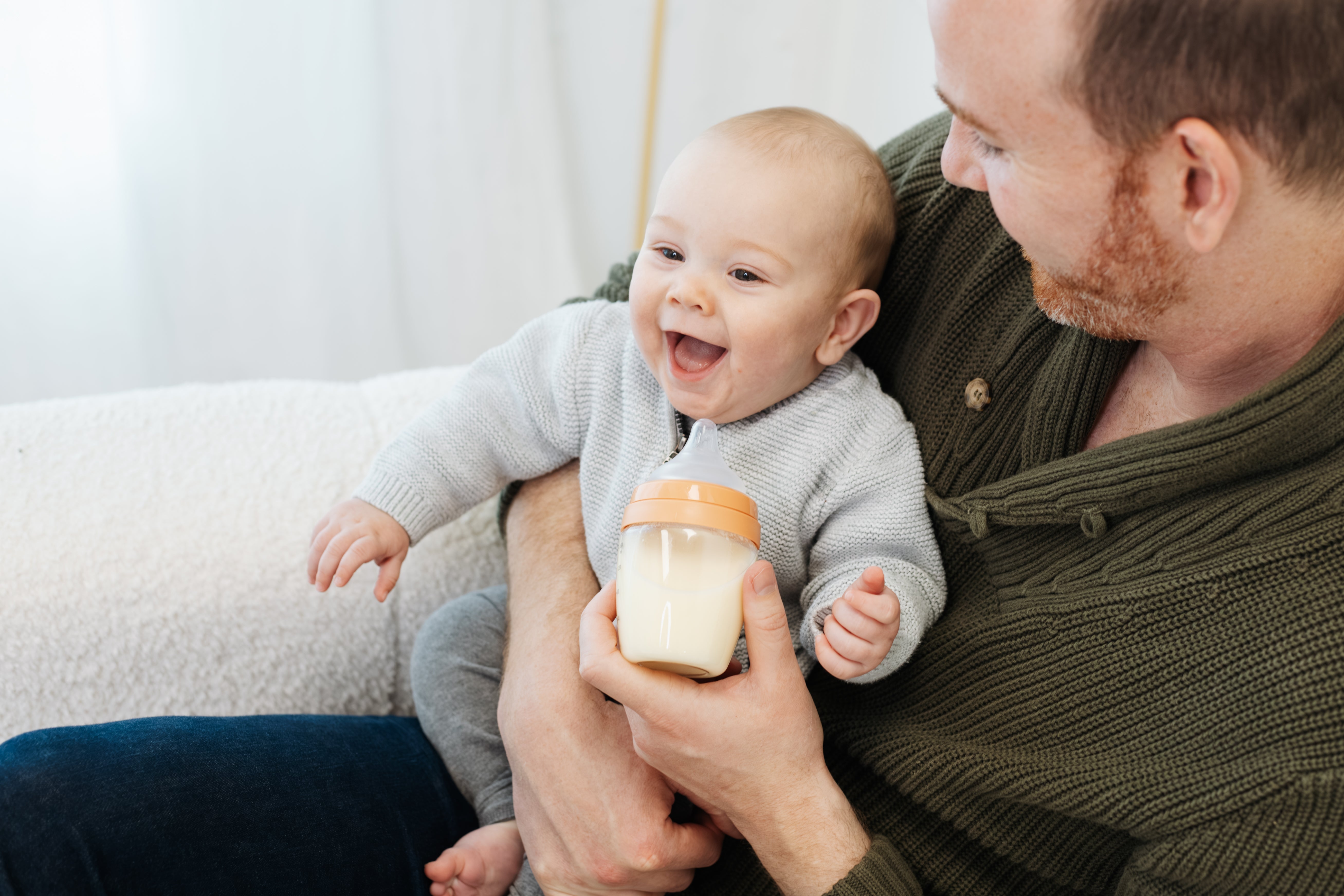 Father feeding infant Quark Baby bottle during developmental milestone moment