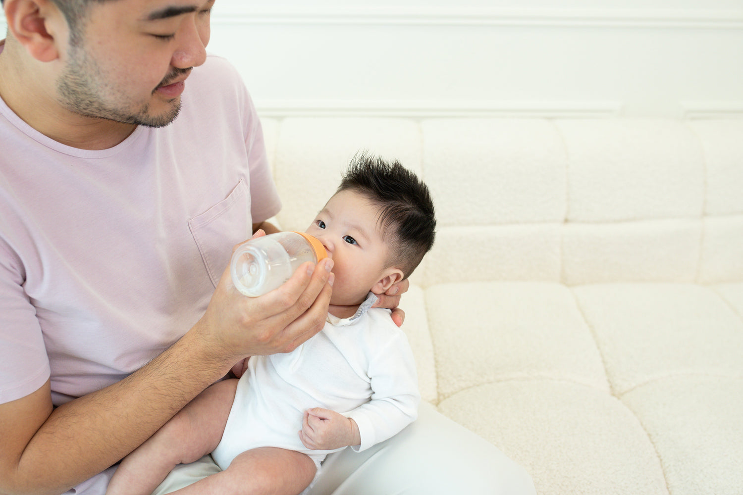 Adult feeding infant with Quark Baby bottle during caregiving moment