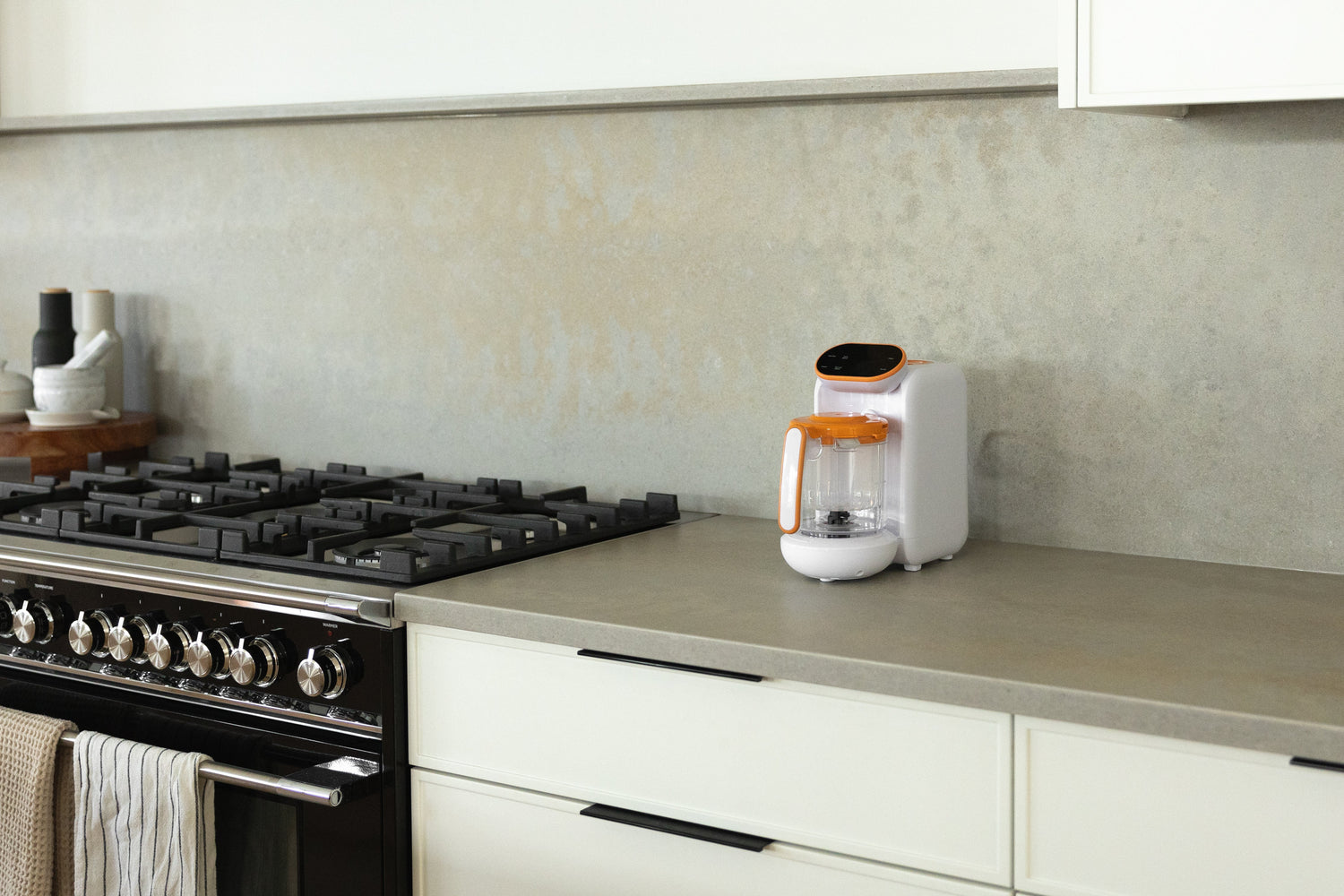 Quark Baby Quook blender on kitchen counter next to gas range in modern home setting.