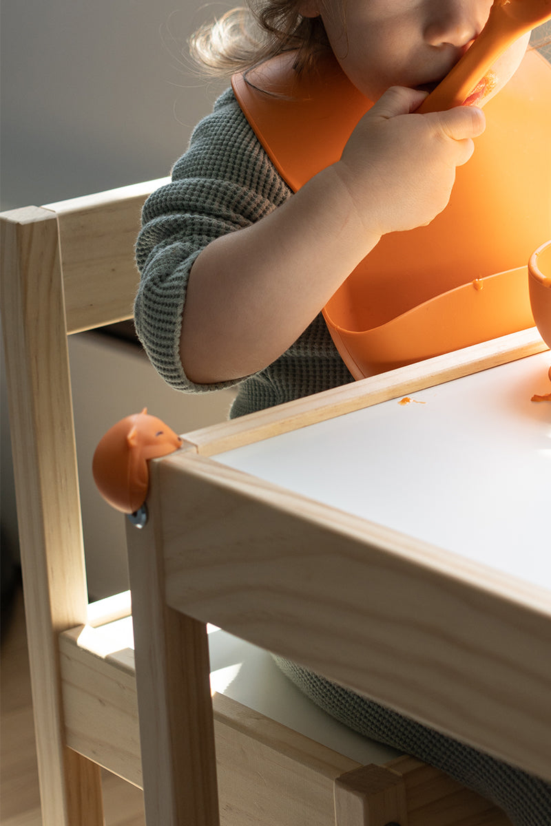 Toddler at wooden table with Quark Foxii silicone corner protectors in playful safety design