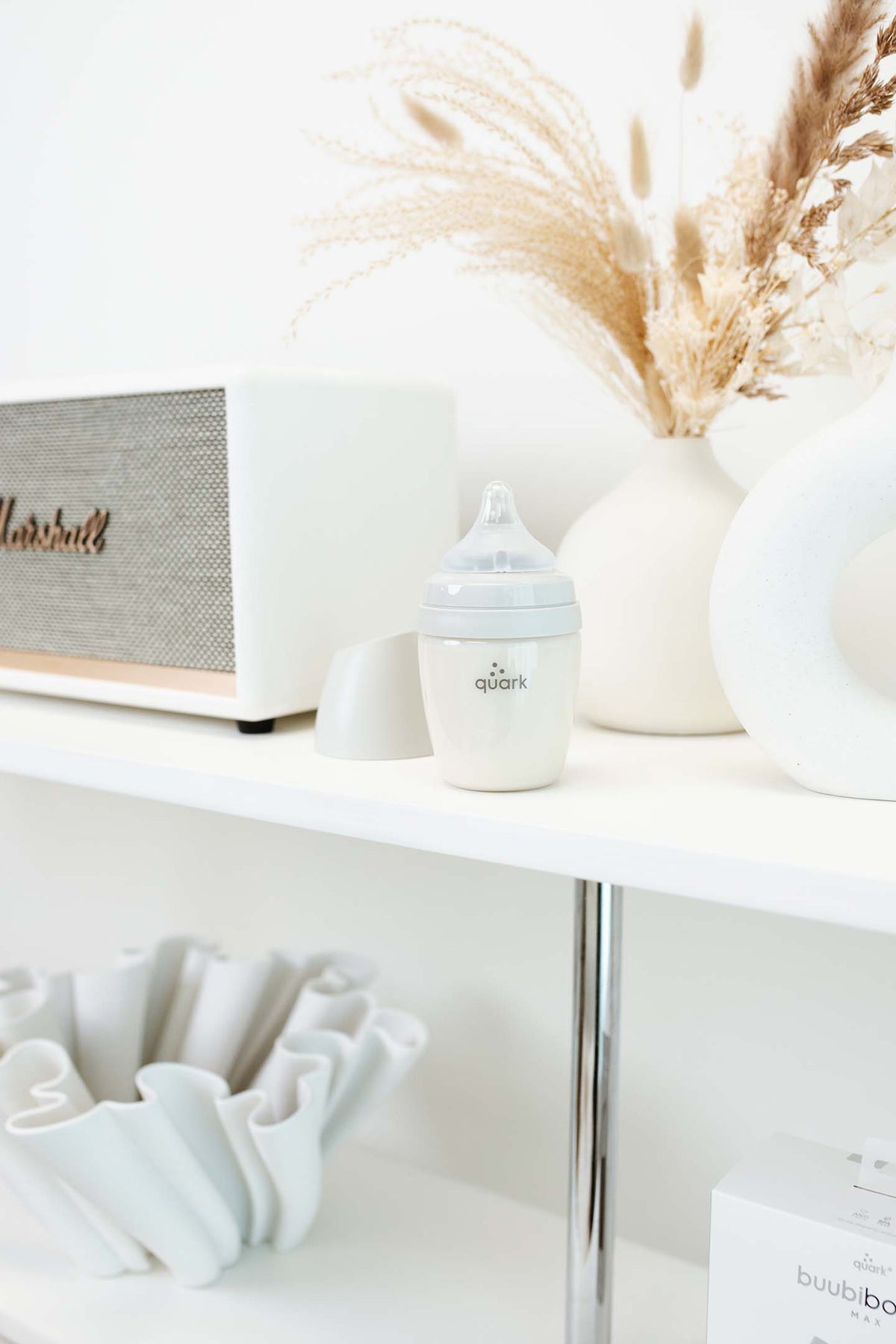 BuubiBottle Mini grey baby bottle on shelf with home decor — shatterproof newborn feeding bottle in natural lifestyle setting