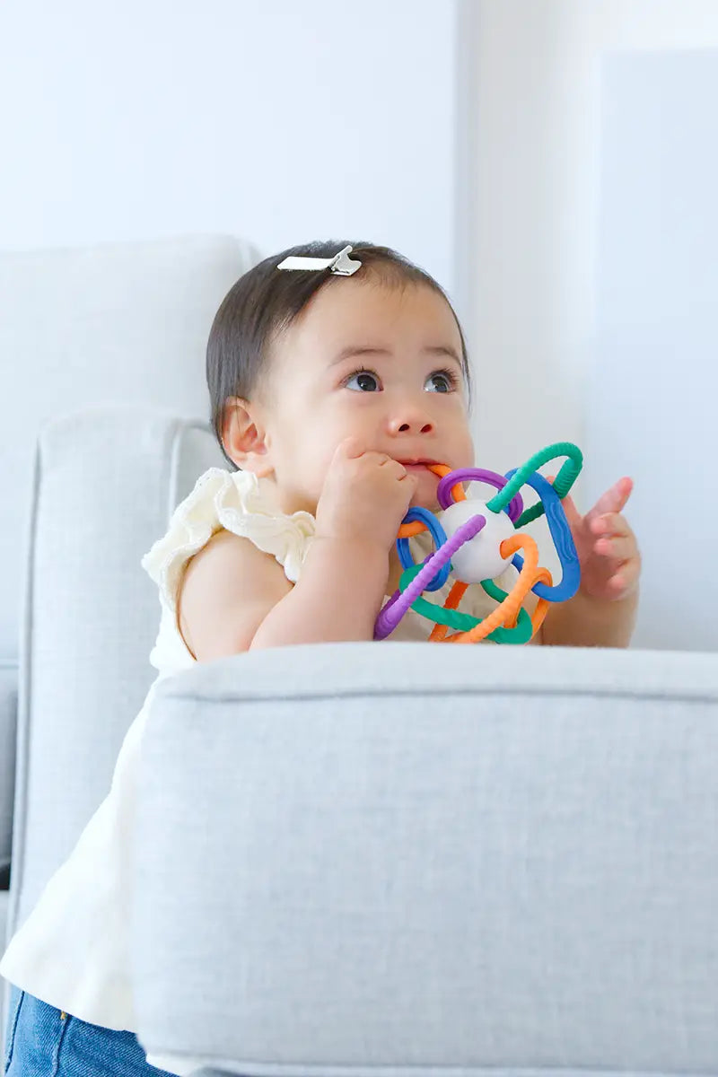 Toddler chewing colorful Quark Thiingy sensory teether toy with textured rings