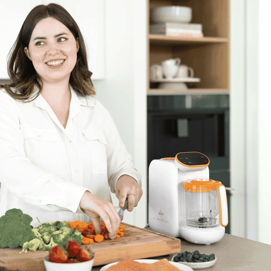 Parent preparing homemade baby food in a kitchen with the Quook baby food maker