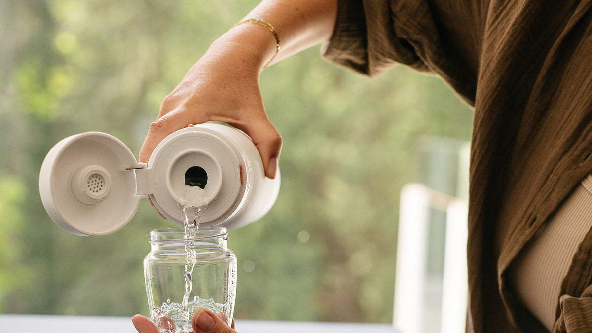 Pouring clean water from the open BuubiBottle Portable Milk Warmer PRO vessel