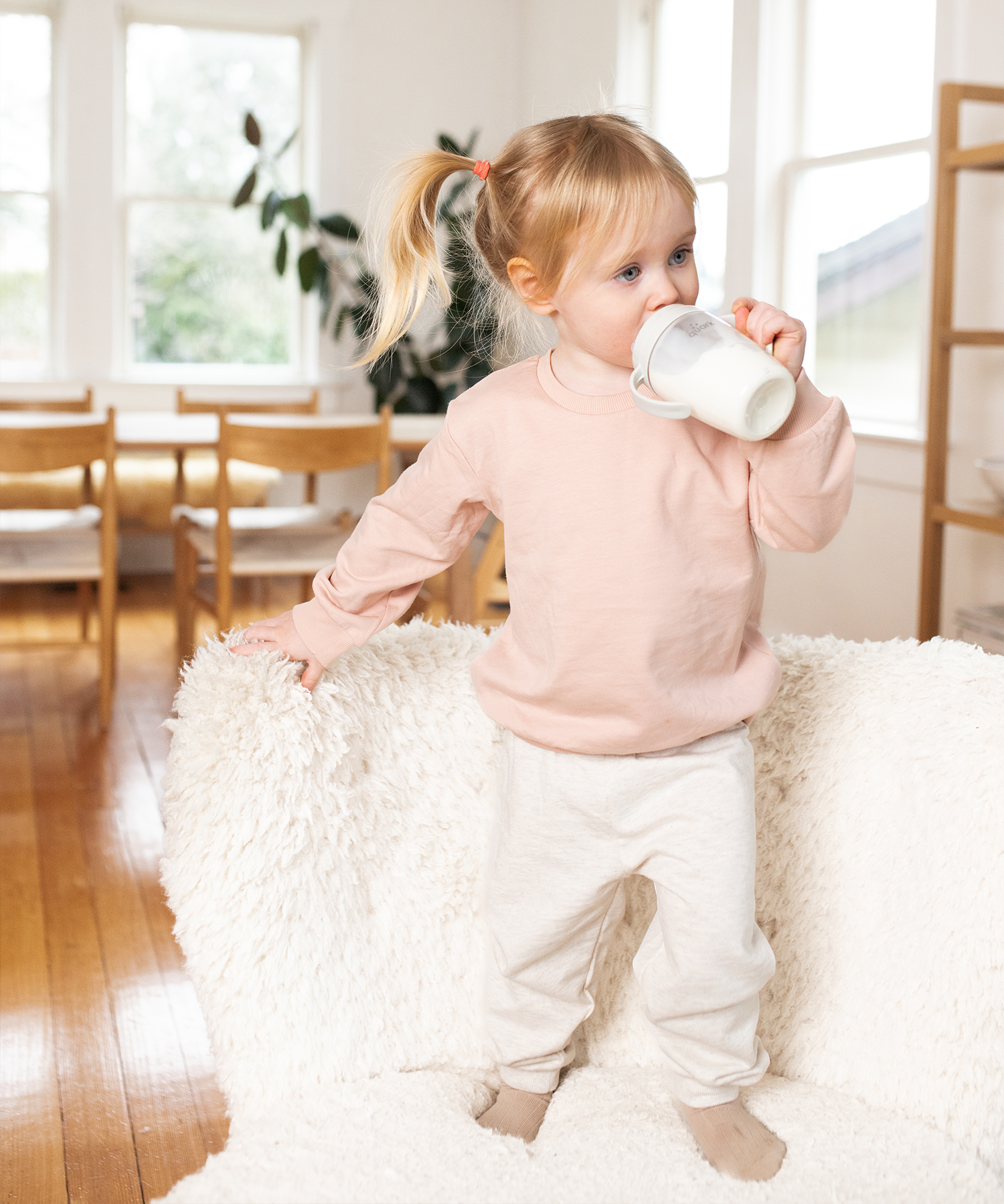 Toddler drinking from Quark Baby sippy cup in bright home setting