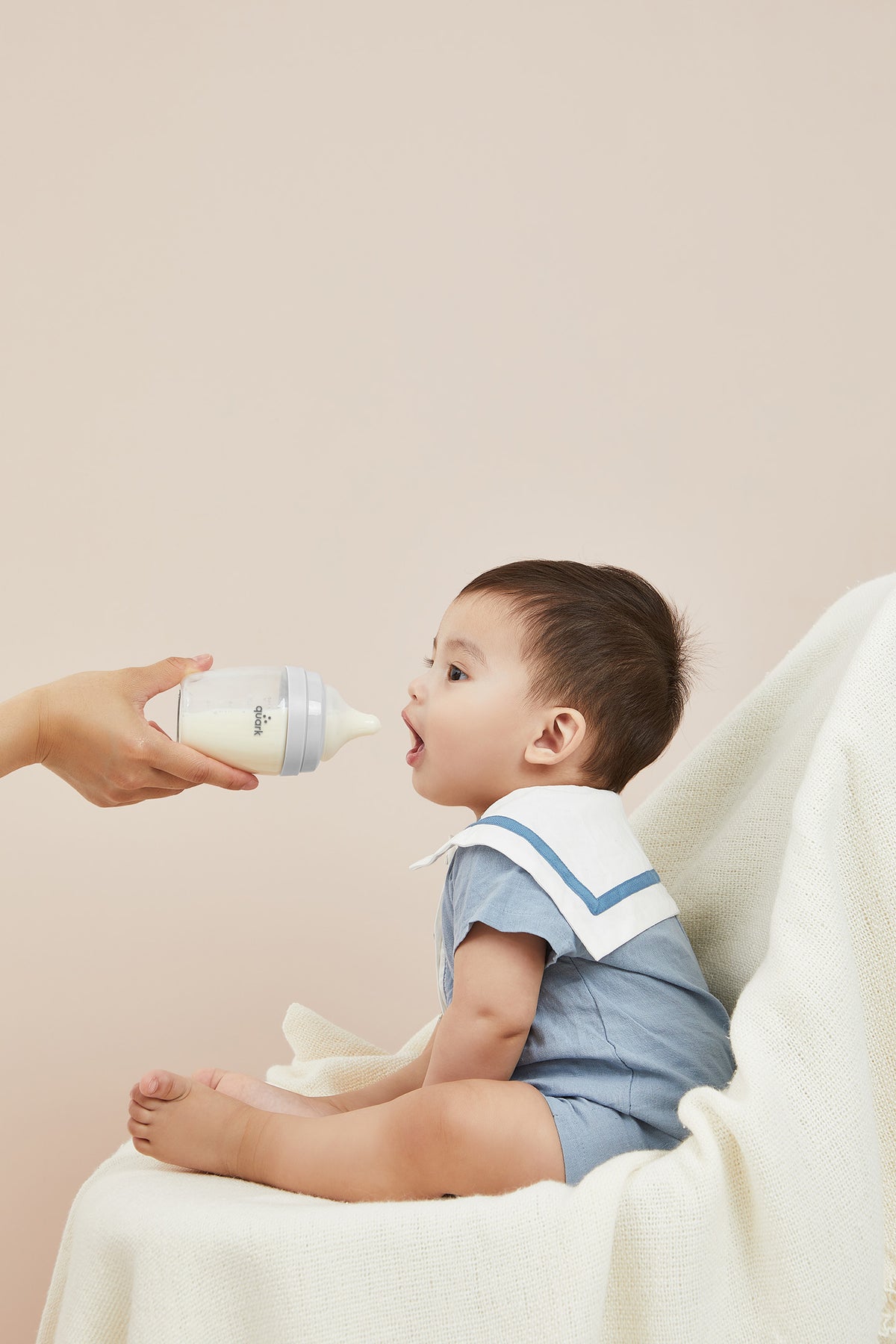 Parent feeding newborn with BuubiBottle Mini 5oz grey bottle — shatterproof baby bottle for breastfed babies and combination feeding