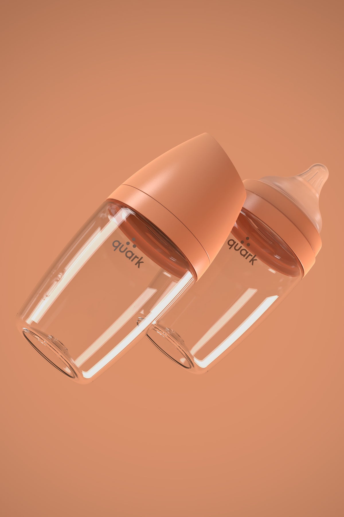 Two Quark BuubiBottle Mini orange hybrid feeding bottles with peach caps angled on matching background