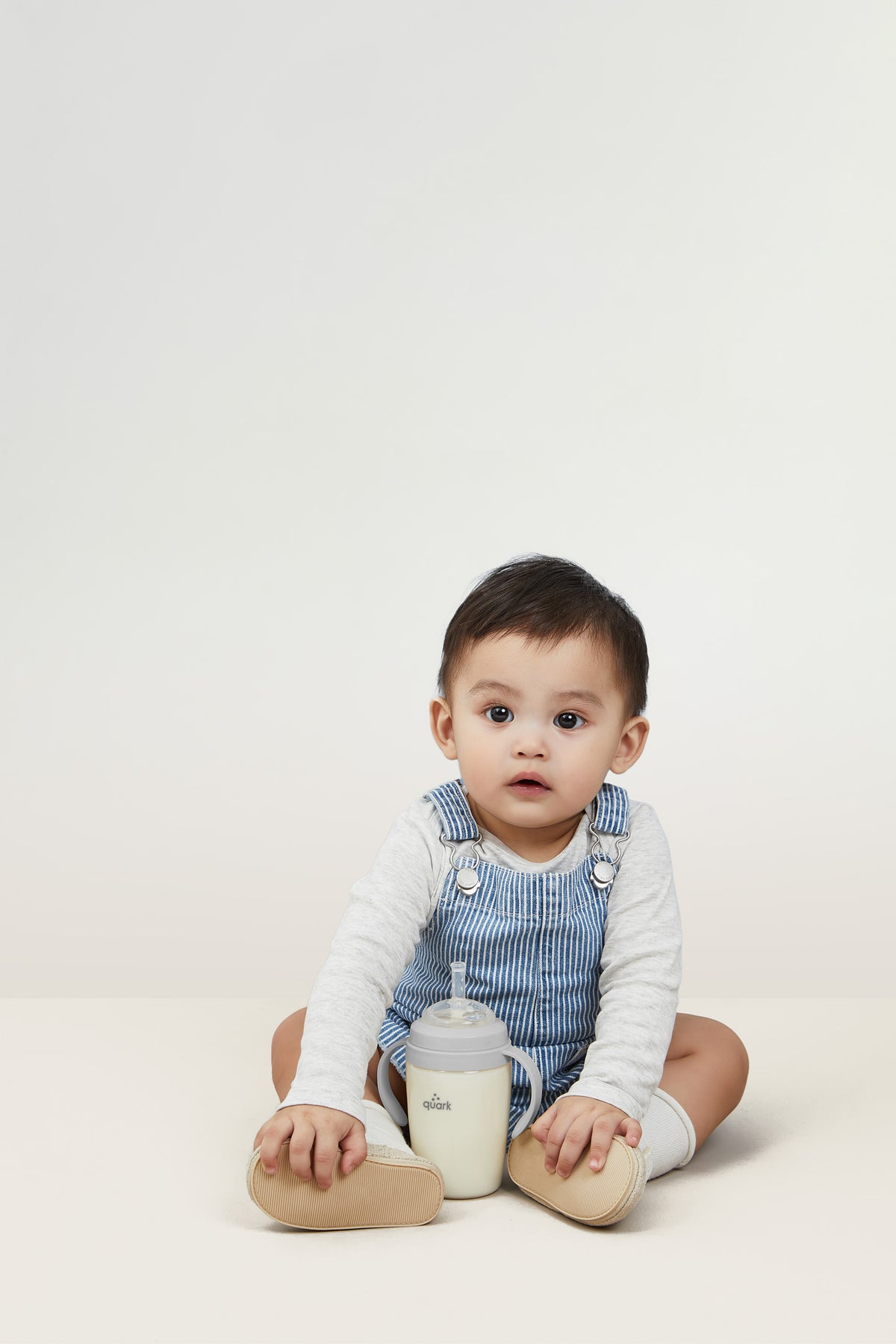 Toddler independently drinking from BuubiBottle Sip grey straw cup — easy-grip toddler straw cup for bottle transition, shatterproof design