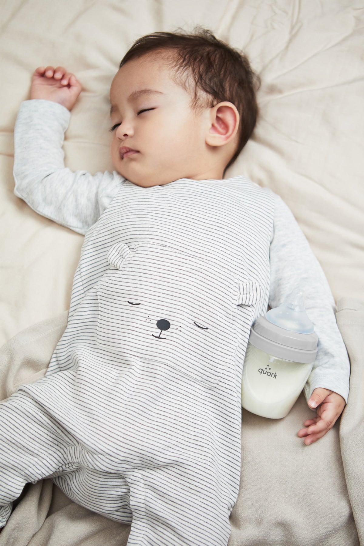Sleeping newborn beside BuubiBottle Max grey 8oz baby bottle — shatterproof anti-colic bottle safe for bedside feeding