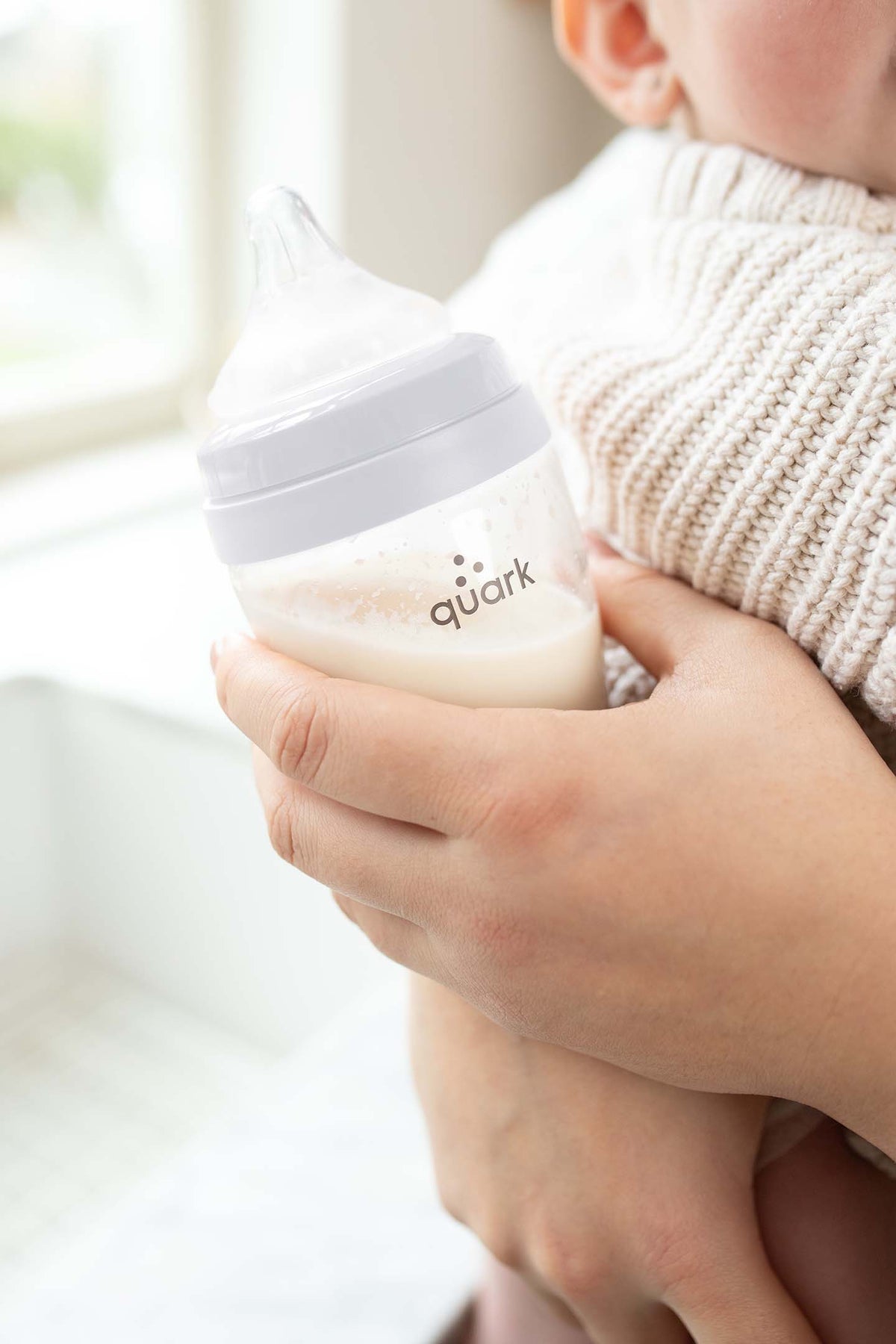 Parent holding BuubiBottle with RealFeel nipple during feeding — breast-shaped silicone nipple for combination breastfeeding and bottle feeding