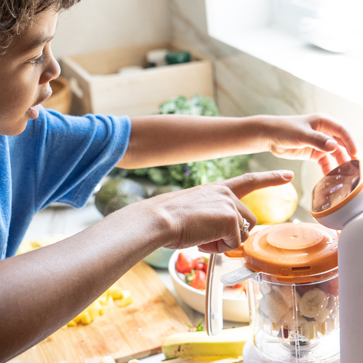 Young child helping prepare homemade baby food with Quook baby food maker — easy-to-use 5-in-1 steamer and blender for family kitchen