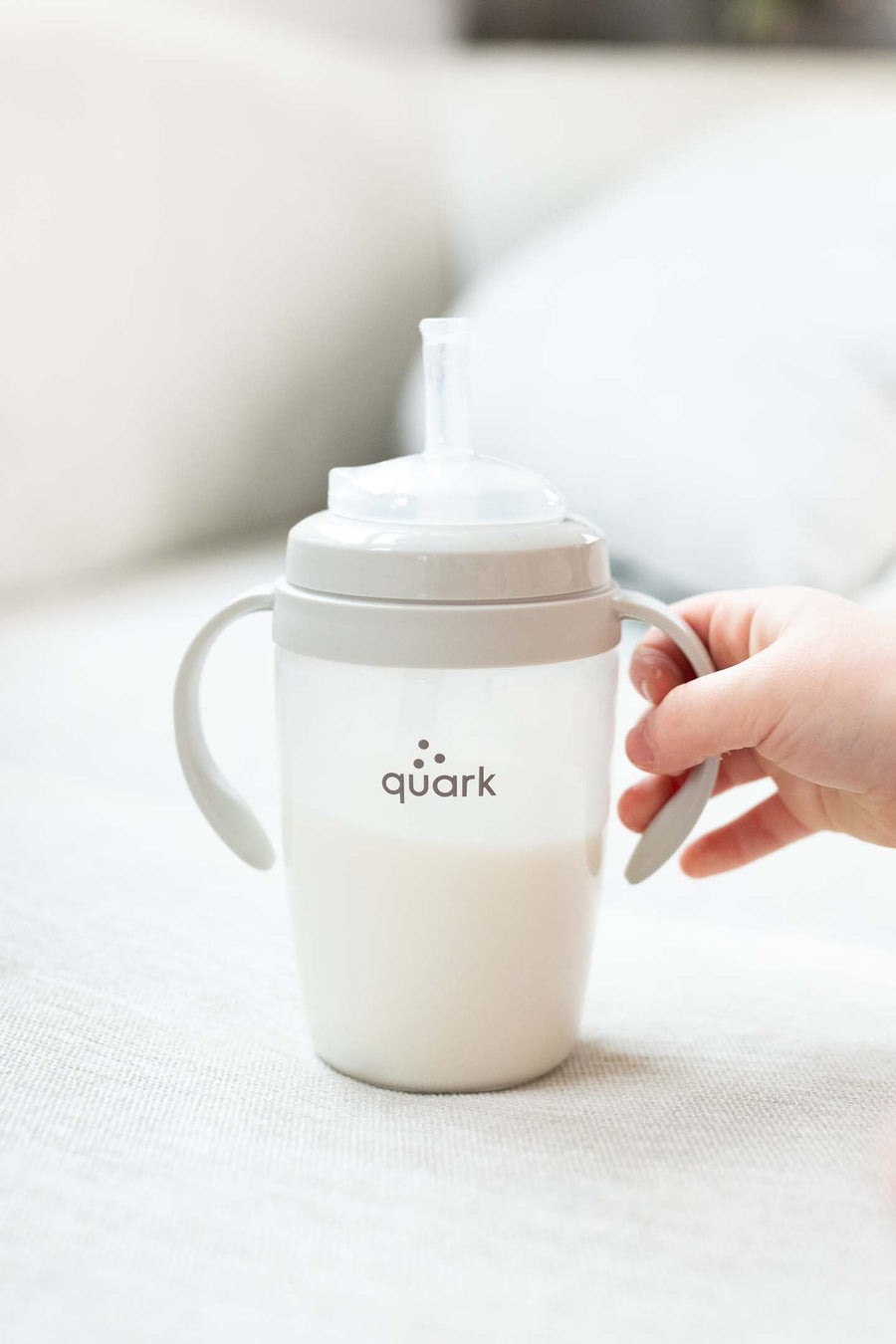 Toddler hand holding BuubiBottle Sip toddler straw cup — bottle-to-cup transition cup from the BuubiBottle product line