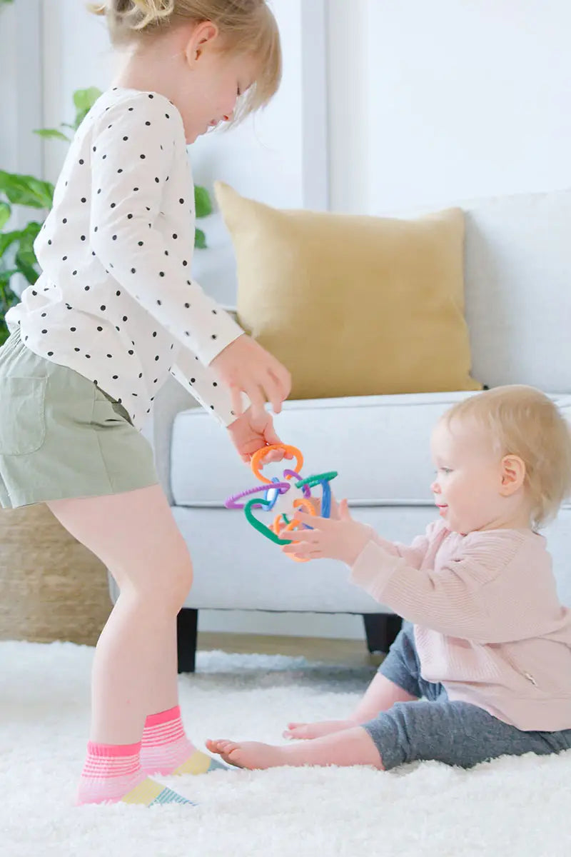 Toddler and baby sharing Quark Thiingy colorful teether toy during interactive sensory play